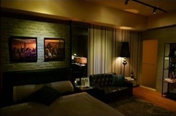 Airbnb listing photo of the room, showing the bed and black leather sofa.